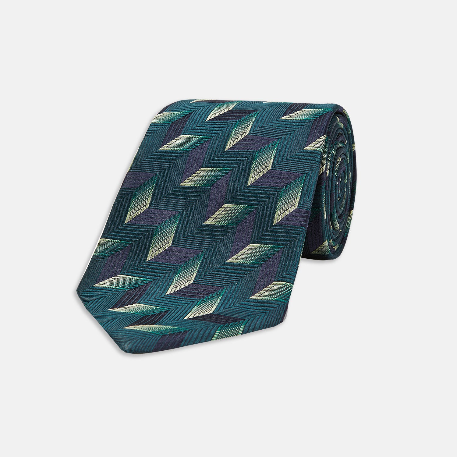 View 1 of product The Turnbull & Asser "The Dark Knight Silk Tie as seen on the Joker" is shown rolled up, featuring a teal zigzag geometric pattern with blue, green, and cream diamonds on a white background.