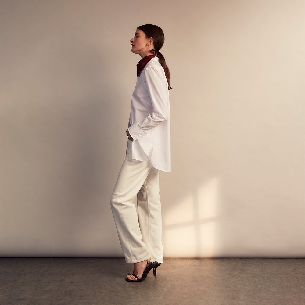 The White Cotton Lauren Shirt by Turnbull & Asser, featuring a stand collar, button-down front, and elongated body, is laid flat on a plain white background.