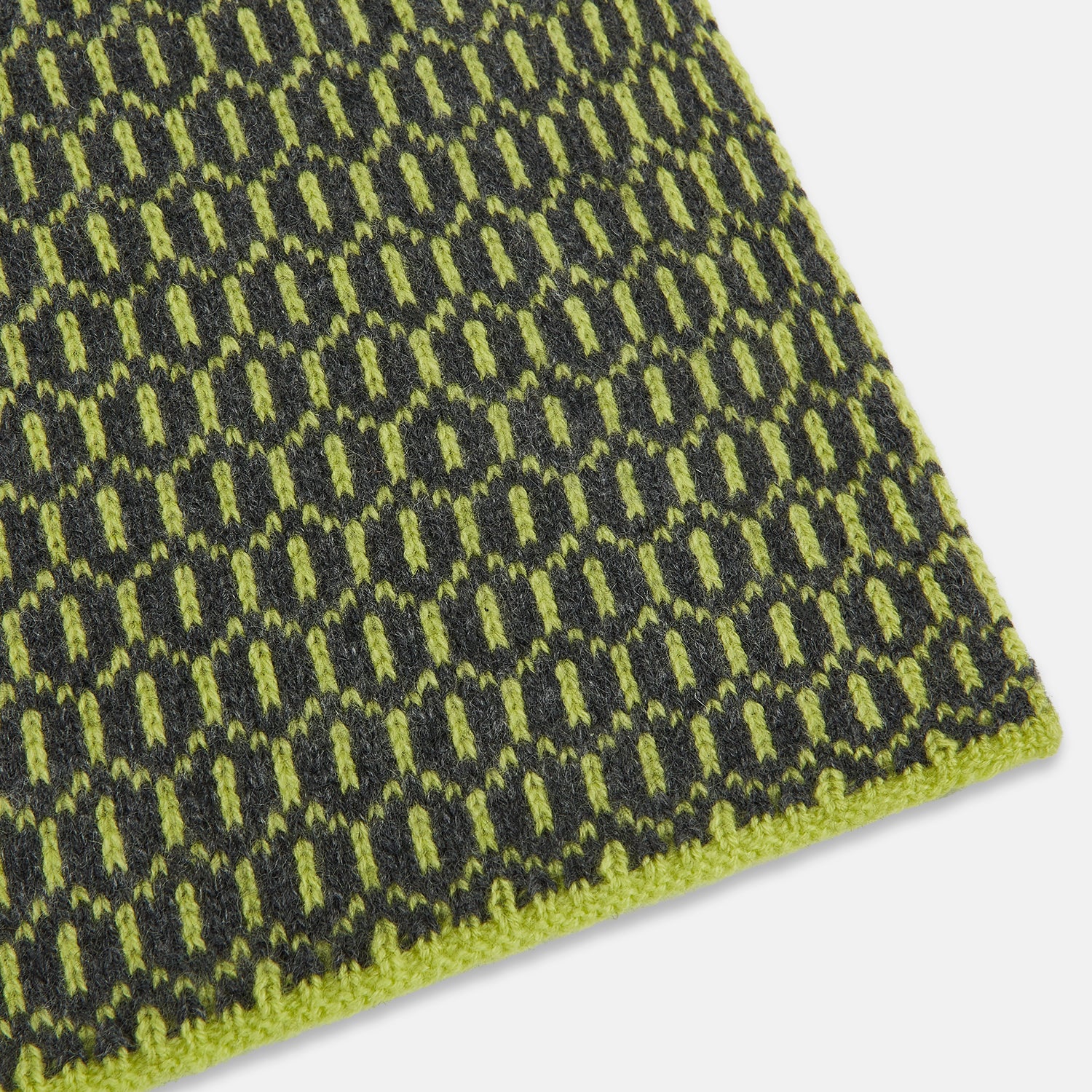 Image 2 of product The Turnbull & Asser Graphite and Chartreuse Lemon Hexagon Cashmere Knitted Scarf features a geometric pattern in green and yellow tones, neatly folded to show both ends—an essential accessory with luxurious softness.