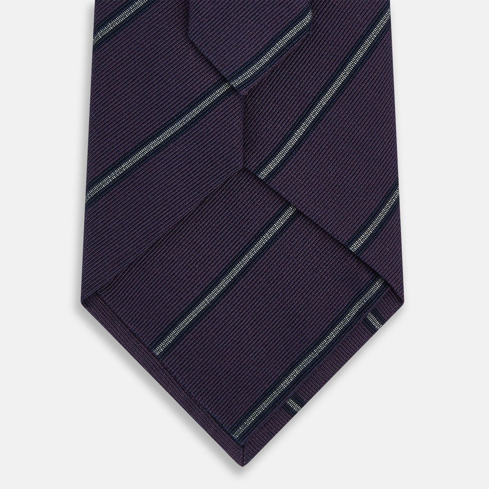 The Turnbull & Asser Purple Multi Stripe Silk Blend Tie, featuring thin light blue diagonal stripes, is neatly rolled on a white background.