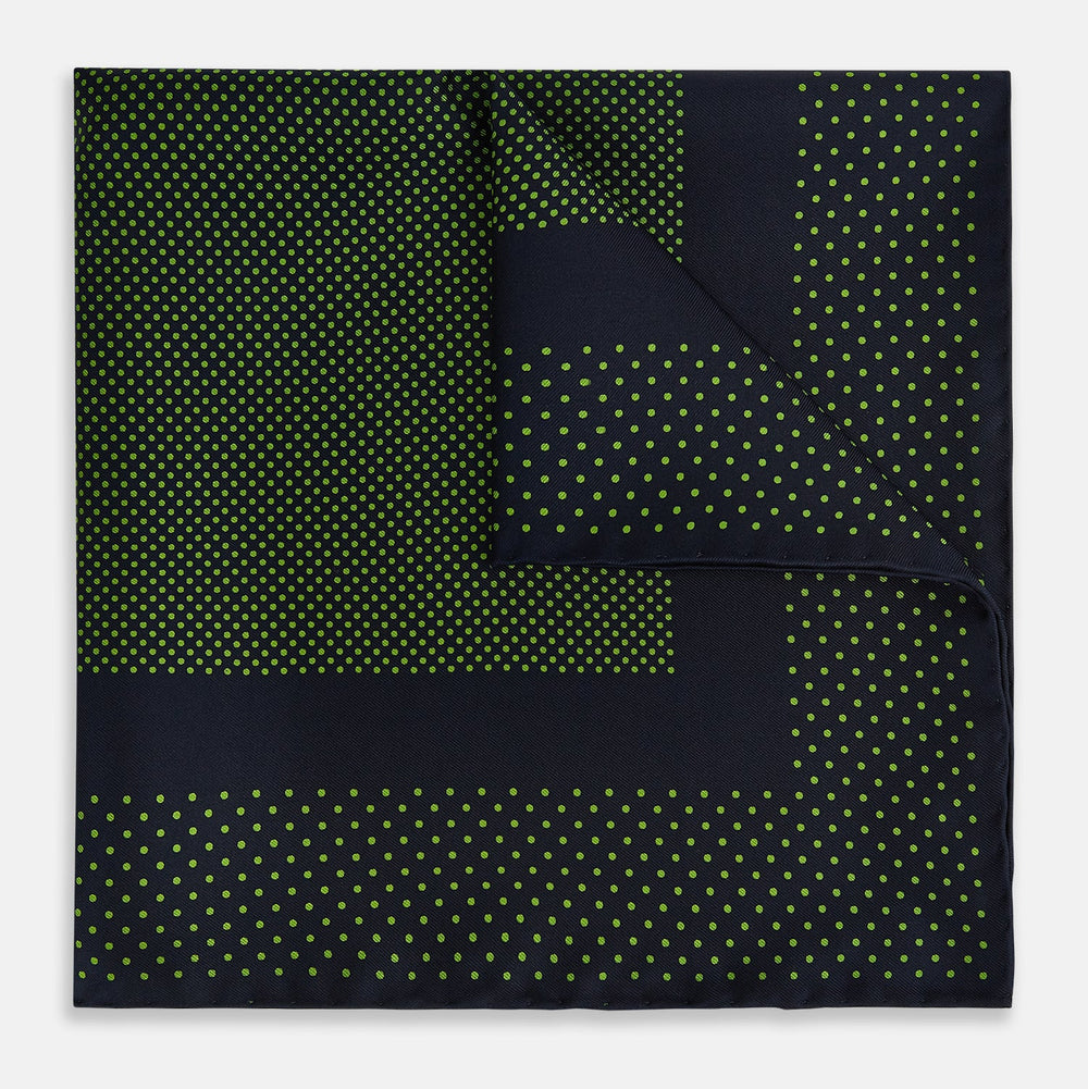 The Turnbull & Asser Navy and Kelly Green Dot Silk Pocket Square features small green dots on navy silk and a folded corner displaying the reverse—an elegant, handmade accessory perfect for enhancing any formal attire.