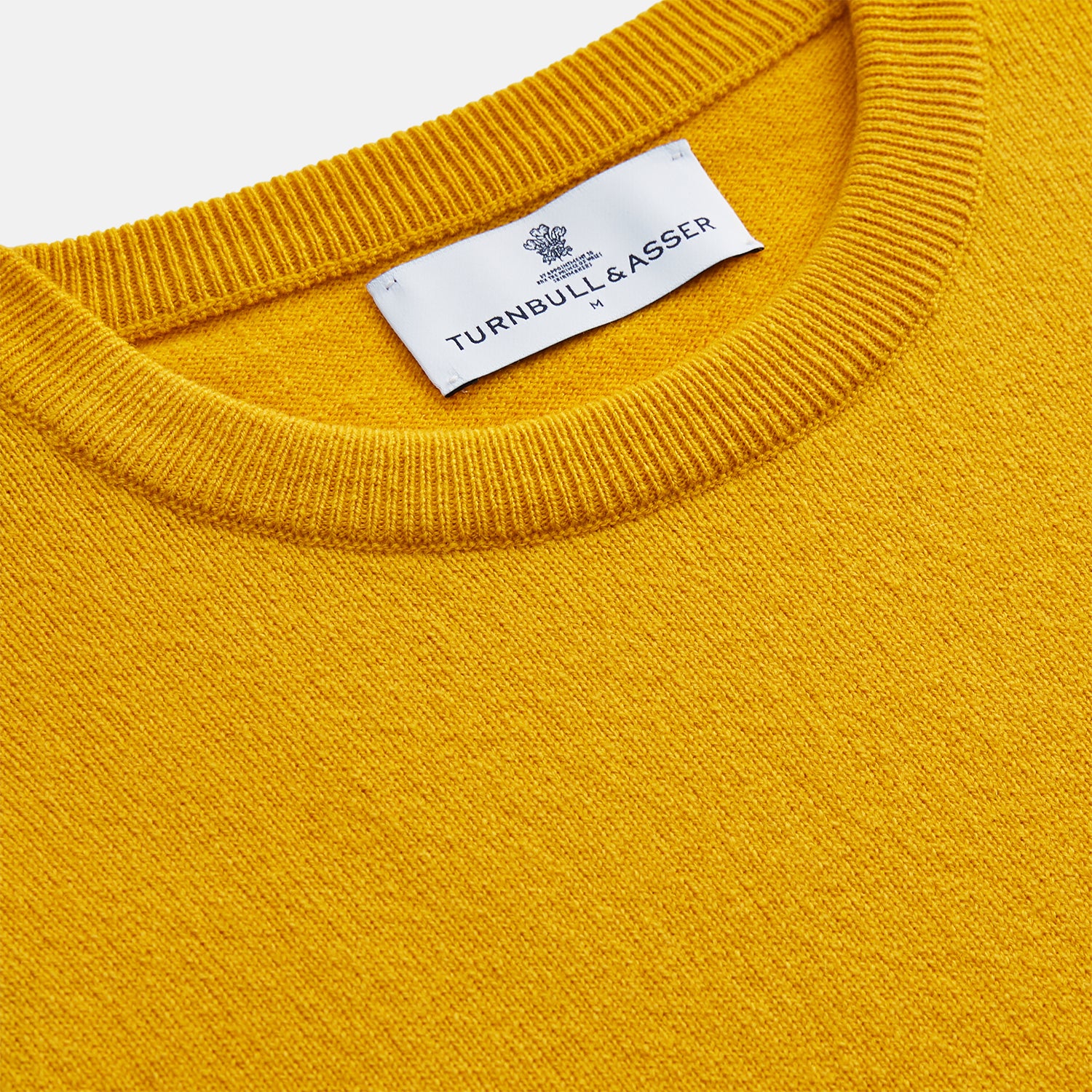 View 2 of product The Gold Glenn Cashmere Crew Neck Jumper by Turnbull & Asser is a luxurious, long-sleeved knit in vibrant mustard yellow, shown laid flat on a white background—an eye-catching essential.