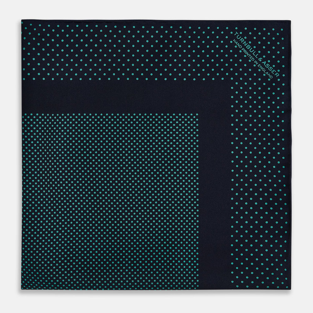 The Turnbull & Asser Navy and Petrol Green Dot Silk Pocket Square features handmade craftsmanship with petrol green polka dots and a darker border, elegantly displayed on a white background.