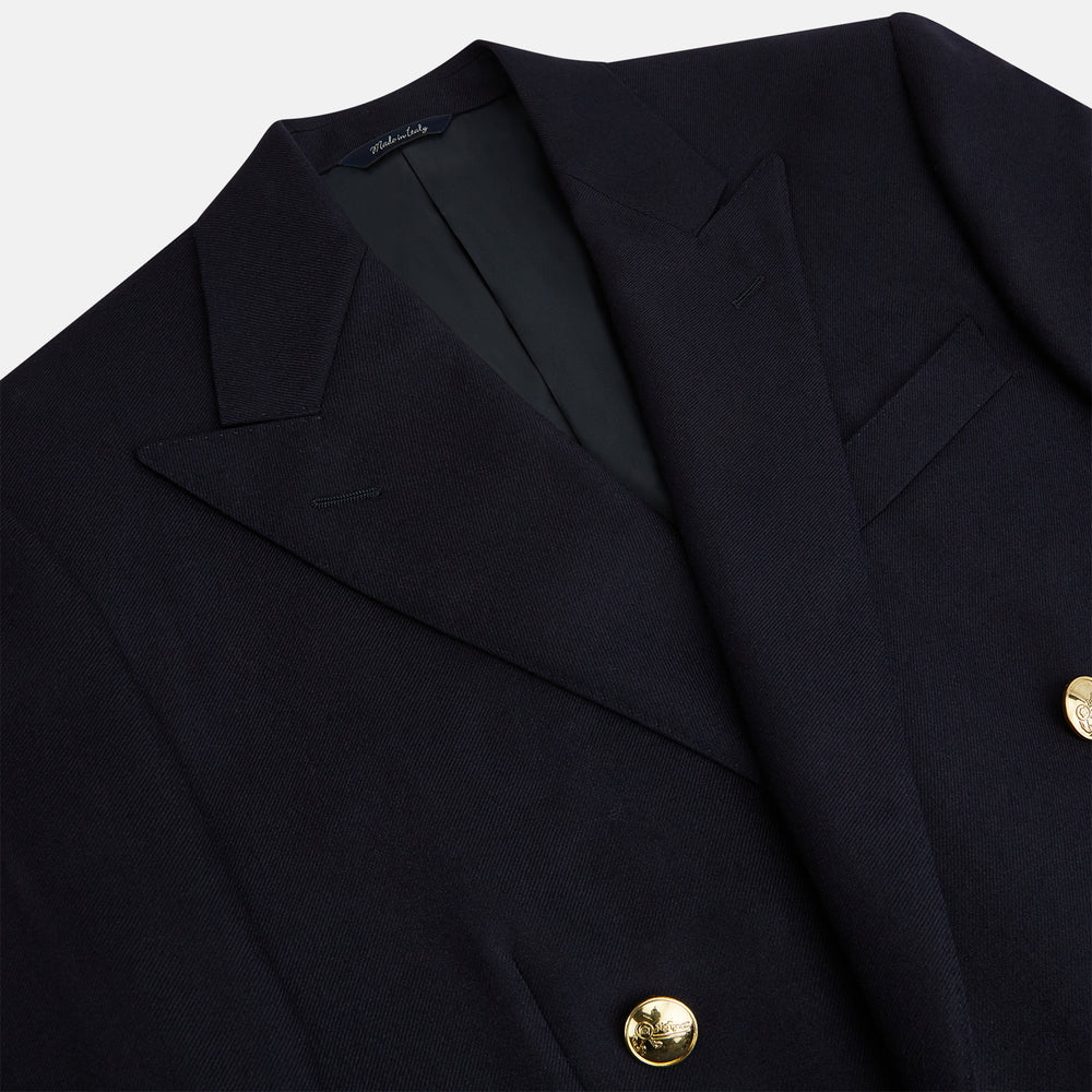 The Turnbull & Asser Navy Double Breasted Classic Blazer features gold buttons, peaked lapels, and multiple front pockets, exemplifying classic British tailoring against a plain light background.