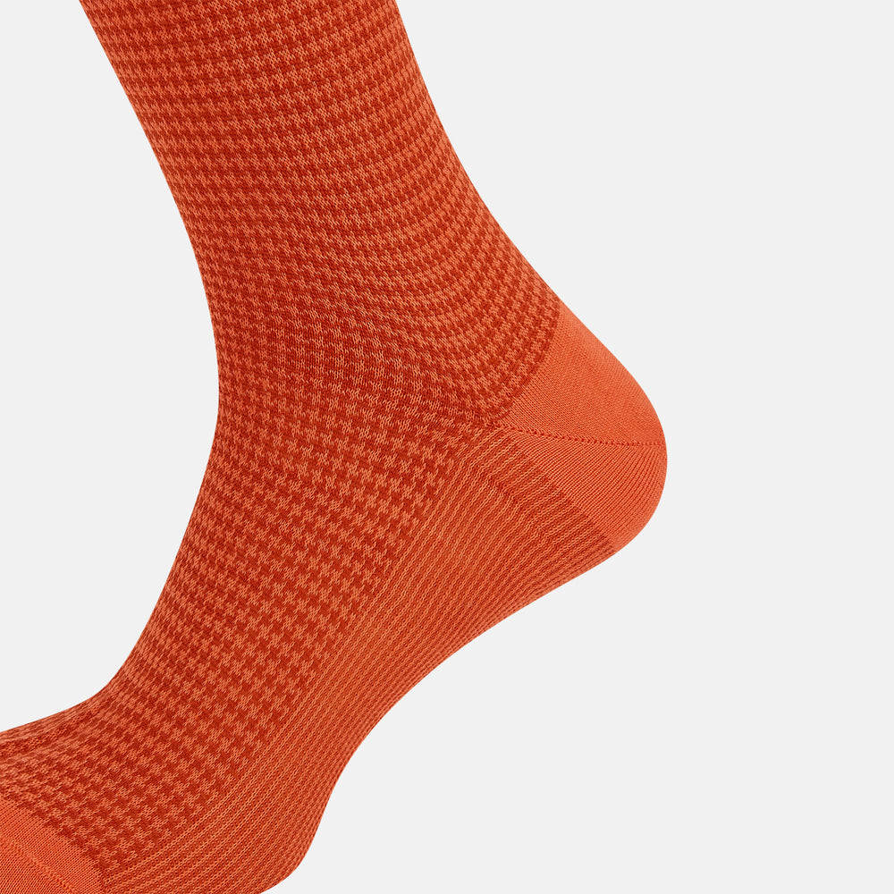 The Orange Houndstooth Mid-Length Socks by Turnbull & Asser feature a bold houndstooth pattern with solid orange toe, heel, and cuff, crafted from soft cotton and shown against a plain white background.