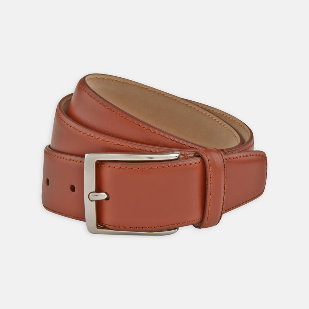 A Red Classic Calf Leather Satin Belt by Turnbull & Asser, coiled neatly with a silver rectangular buckle, set against a plain white background.