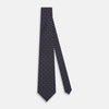View 2 of product The Turnbull & Asser Navy and Red Circle Foulard Silk Tie, featuring a repeating red and white circular motif, is neatly rolled to display classic British craftsmanship.