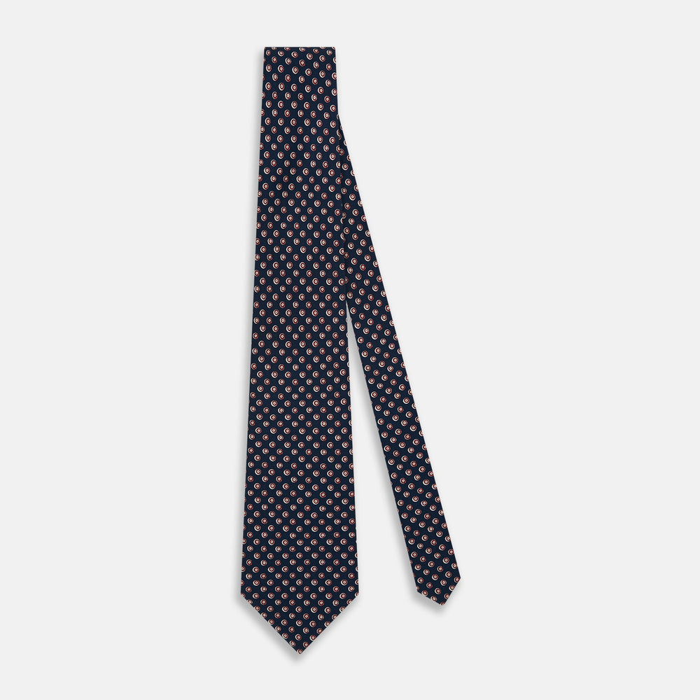 The Turnbull & Asser Navy and Red Circle Foulard Silk Tie, featuring a repeating red and white circular motif, is neatly rolled to display classic British craftsmanship.