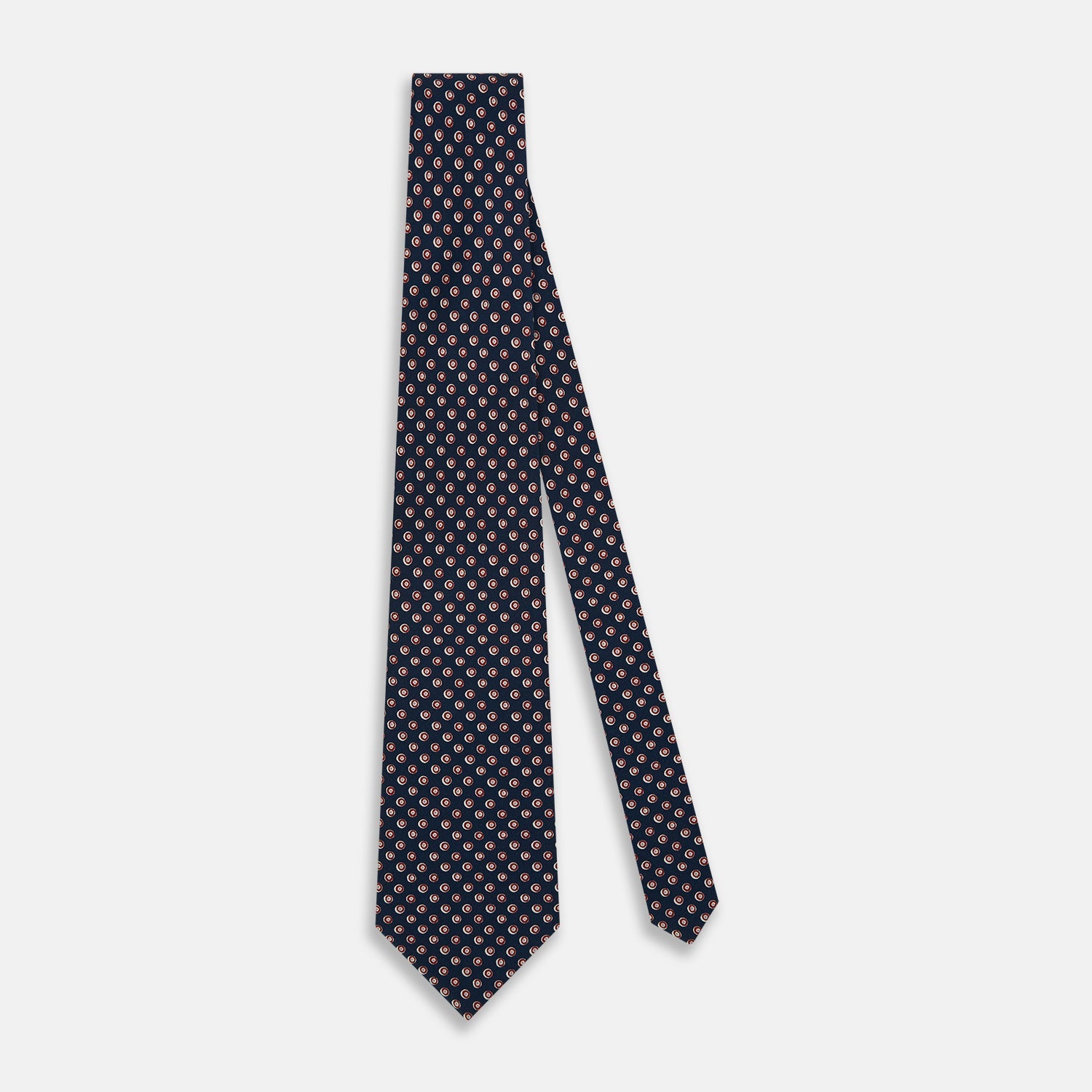 View 2 of product The Turnbull & Asser Navy and Red Circle Foulard Silk Tie, featuring a repeating red and white circular motif, is neatly rolled to display classic British craftsmanship.