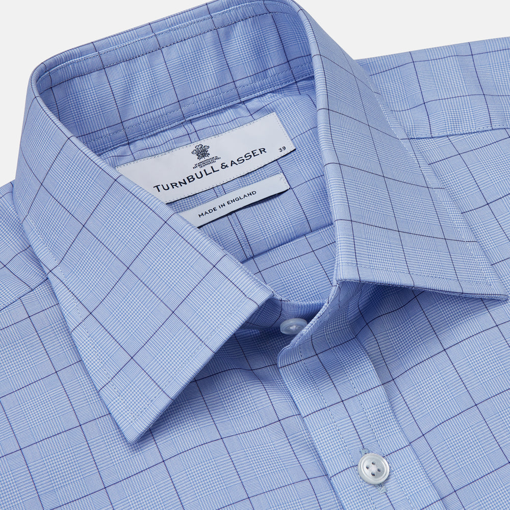 The Blue Prince of Wales Check Mayfair Shirt by Turnbull & Asser is a light blue formal long-sleeve shirt with a subtle check pattern, button-down front, and buttoned cuffs, shown laid flat on a white background.