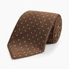 View 1 of product The LACE ON TONE SPOT EARTH RIVER TIE by Turnbull & Asser is a brown woven tie with small light blue dots, shown rolled up on a white background—a stylish accessory for formal outfits.