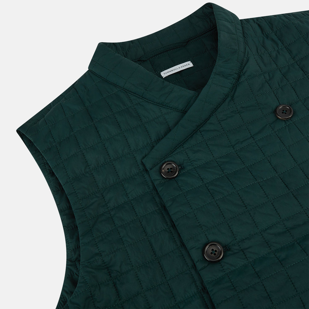 The Turnbull & Asser Forest Green Double-Breasted Quilted Gilet features black buttons, a chest pocket, two zippered side pockets, and an overlapping collar—ideal for layered dressing against a plain white background.