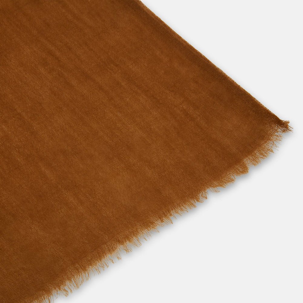 The Turnbull & Asser Coffee Cashmere Scarf features a soft texture and frayed edges for a relaxed, casual vibe. Loosely tied with both ends hanging down, this luxury accessory stands out against a plain white background.