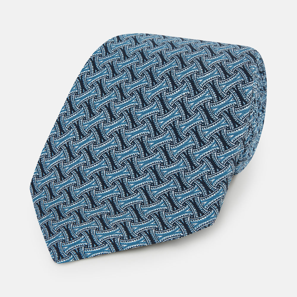 A rolled-up Turnbull & Asser Pale Blue and Navy Weave-Patterned Printed Silk Tie is shown against a white background.