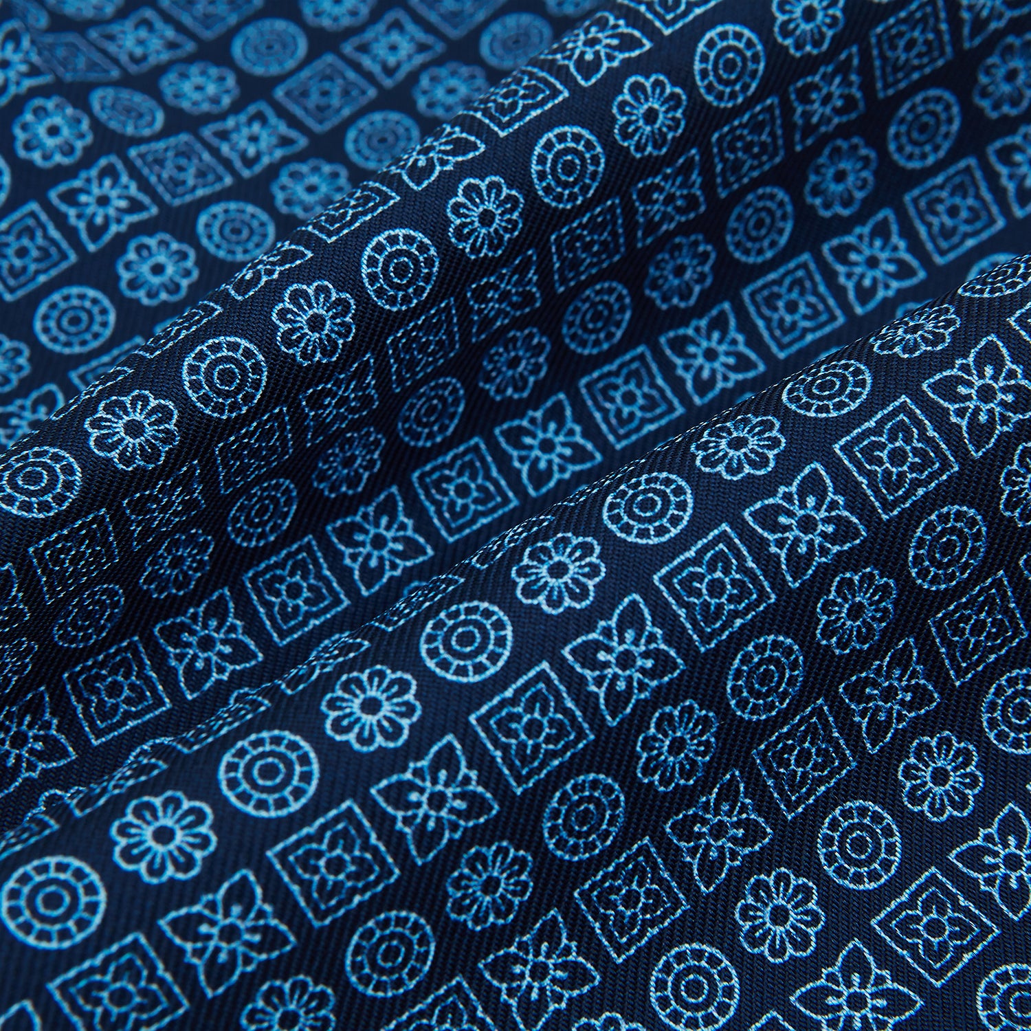 View 4 of product The Turnbull & Asser Dark Navy Floral Tile Pattern Printed Silk Cravat features a British-inspired light blue floral tile design, elegantly displayed on a white background.