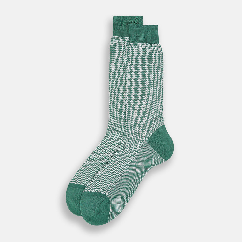 The Turnbull & Asser Ivory Houndstooth Mid-Length Sock features a green and white houndstooth pattern with solid green cuff, heel, and toe accents. Displayed on a plain white background.