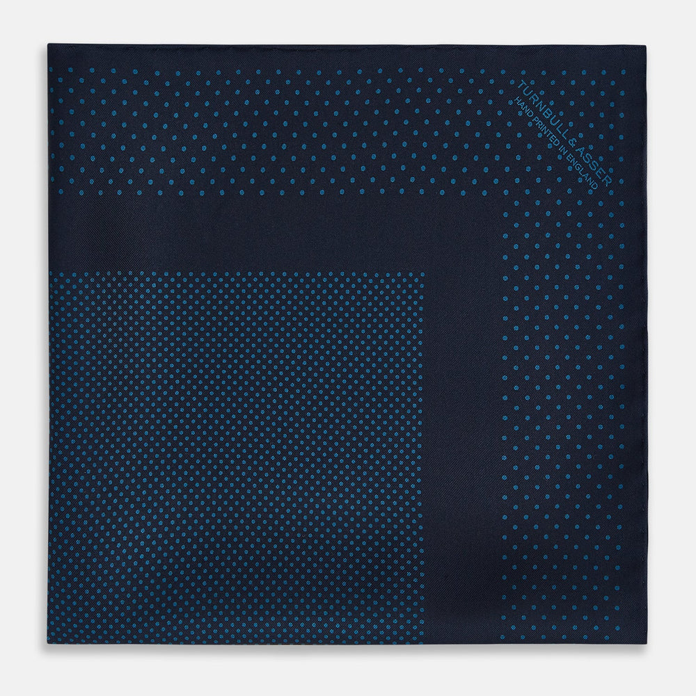 The Turnbull & Asser Navy and Blue Dot Silk Pocket Square features a handmade design in navy silk with small light blue dots and a crisp border, finished with one corner folded to display the reverse side.