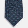 View 3 of product The Turnbull & Asser Navy Medallion Silk Tie features a rolled-up navy silk design with light blue circular medallions and small cross motifs.