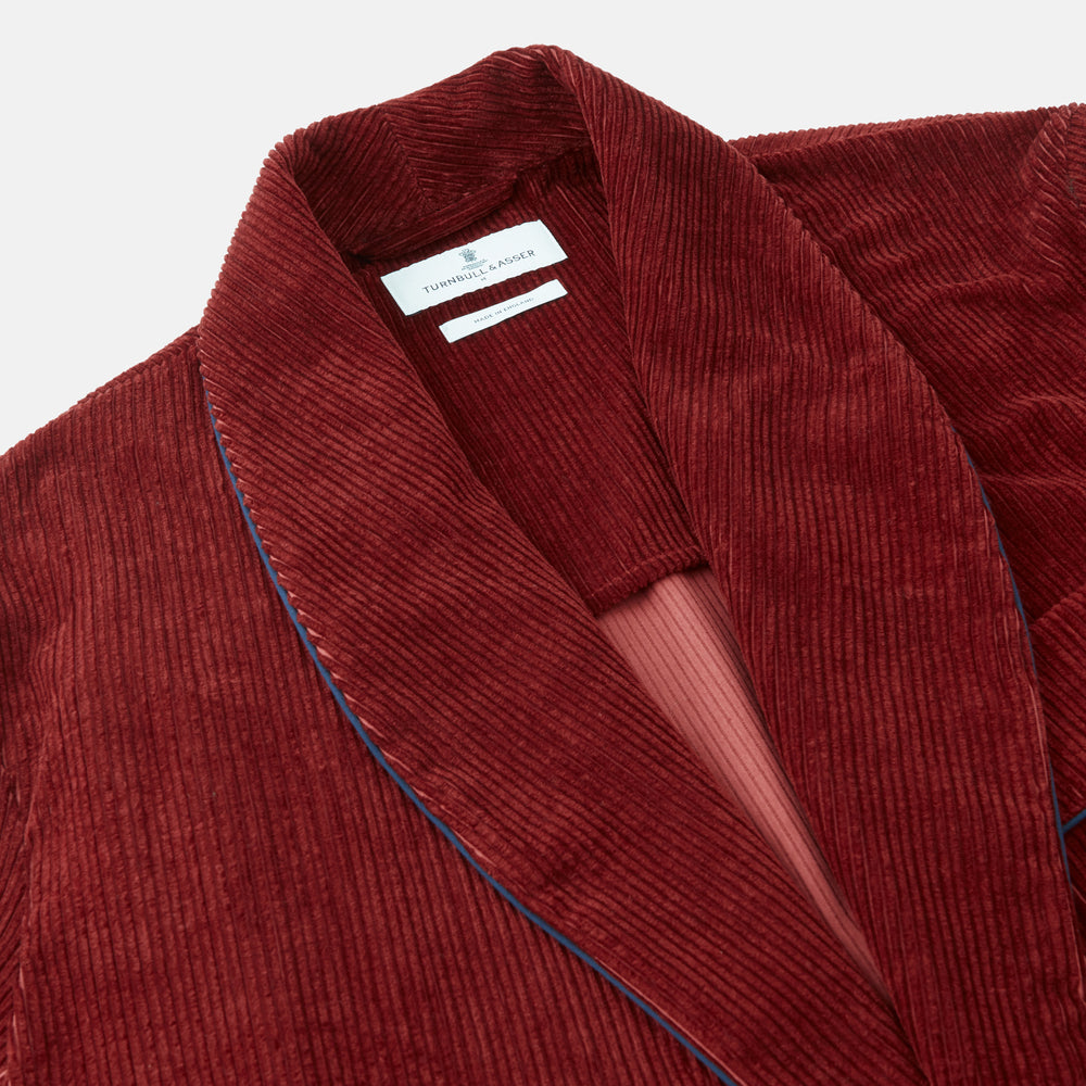 The Turnbull & Asser Burgundy Linen & Cotton Cord Gown, expertly made in England, features a shawl collar, patch pockets, and a matching fabric belt—shown here on a white background.