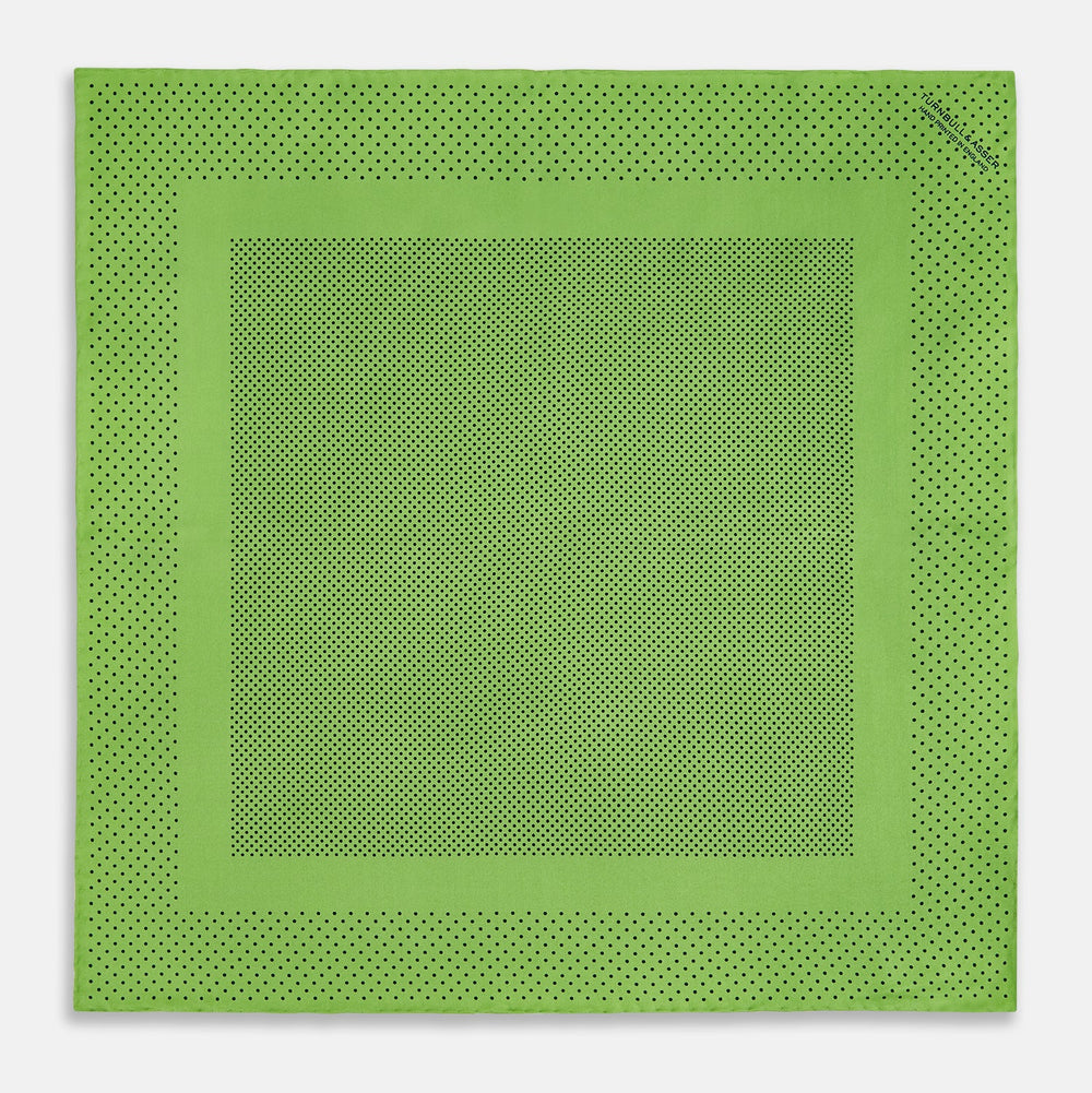 The Turnbull & Asser Kelly Green Dot Silk Pocket Square features small black polka dots and is shown neatly folded to showcase both its front and inner sides.