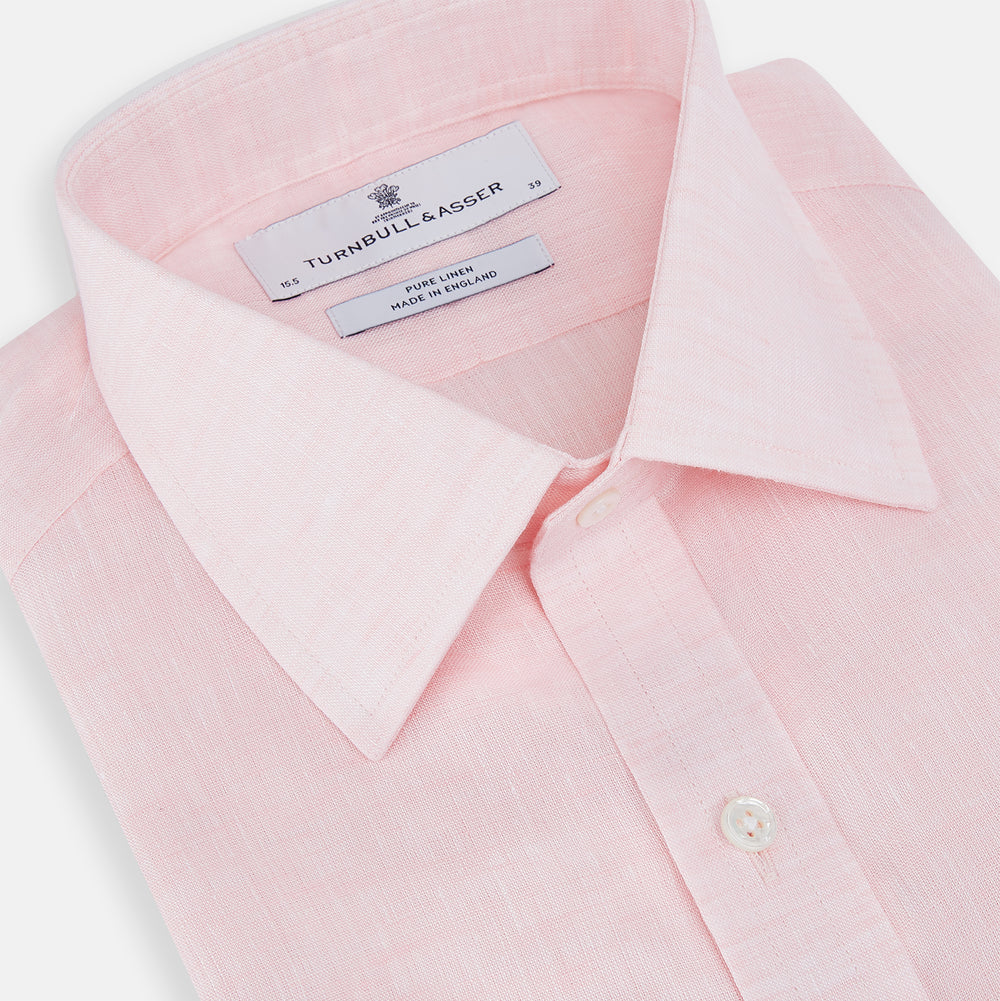 The Turnbull & Asser Pale Pink Linen Mayfair Shirt features a classic, formal style with long sleeves, a collar, and white buttons. Shown laid flat on a white background.