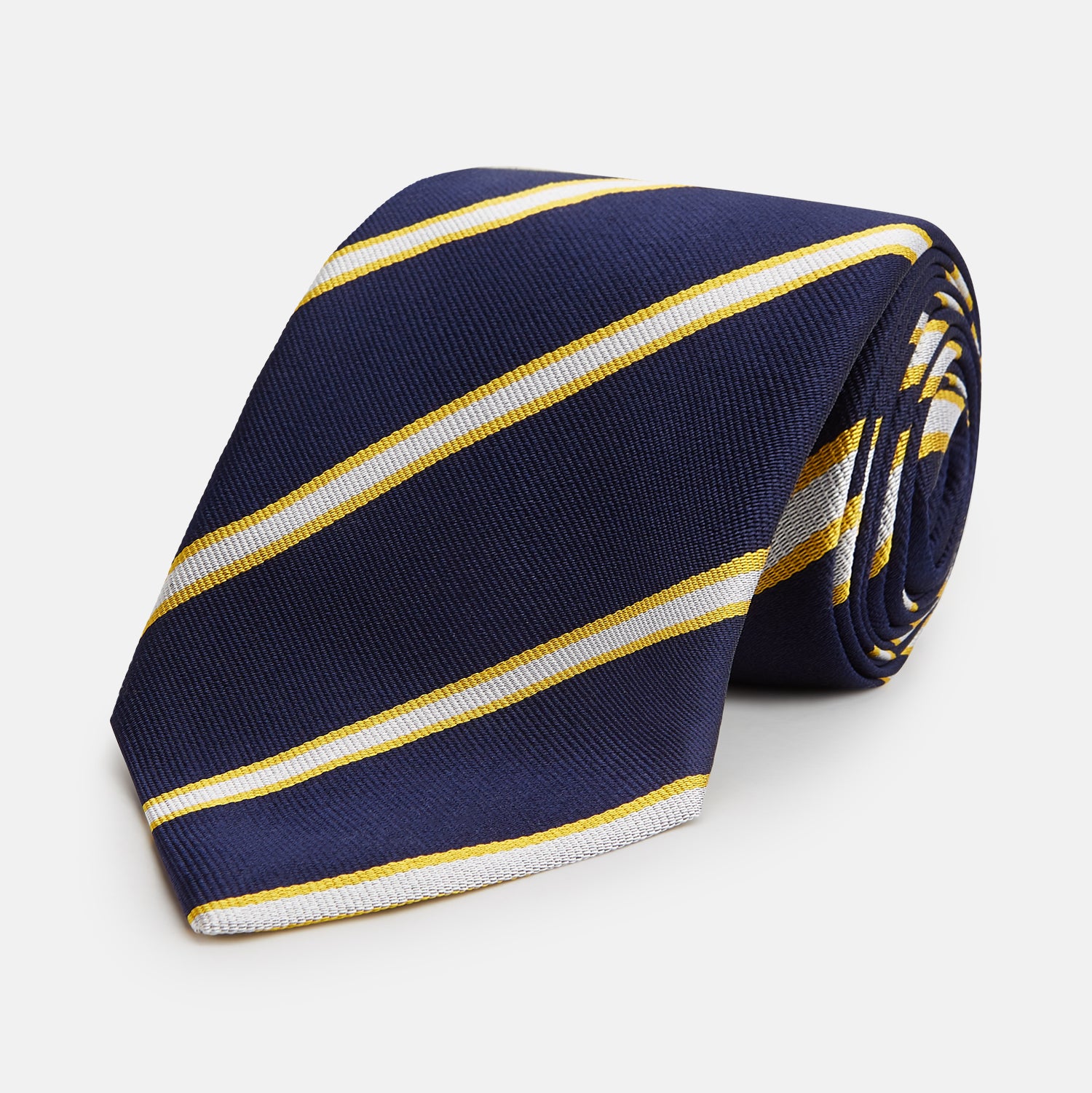 View 1 of product The Yellow and White Blazer Silk Tie by Turnbull & Asser, featuring diagonal white and yellow stripes on navy blue, is shown rolled up against a light gray background.