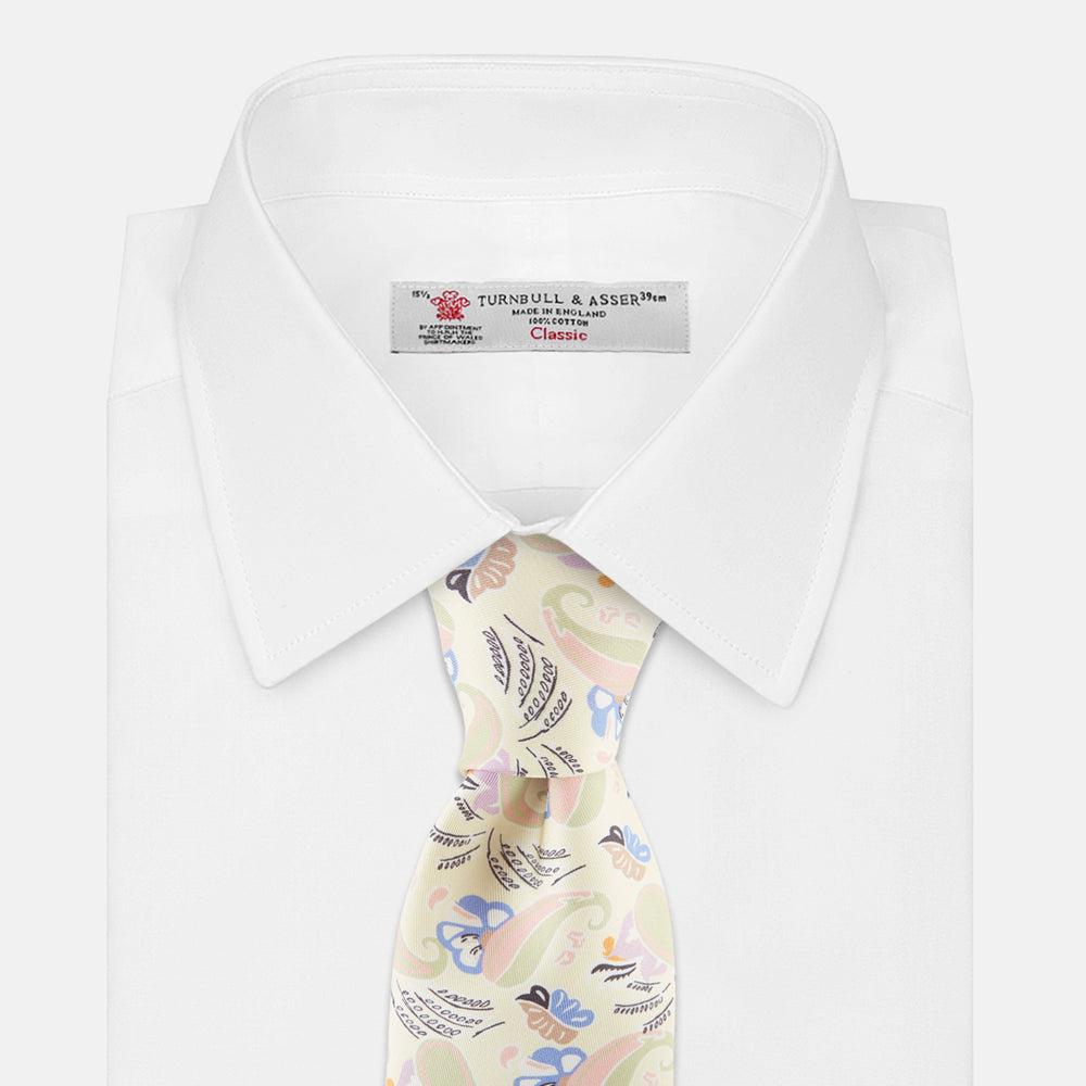 A rolled-up Cream Multi Bloomsbury-Inspired Pattern Silk Tie by Turnbull & Asser, featuring a pastel floral and paisley design in green, blue, pink, and orange tones, displayed on a white background.