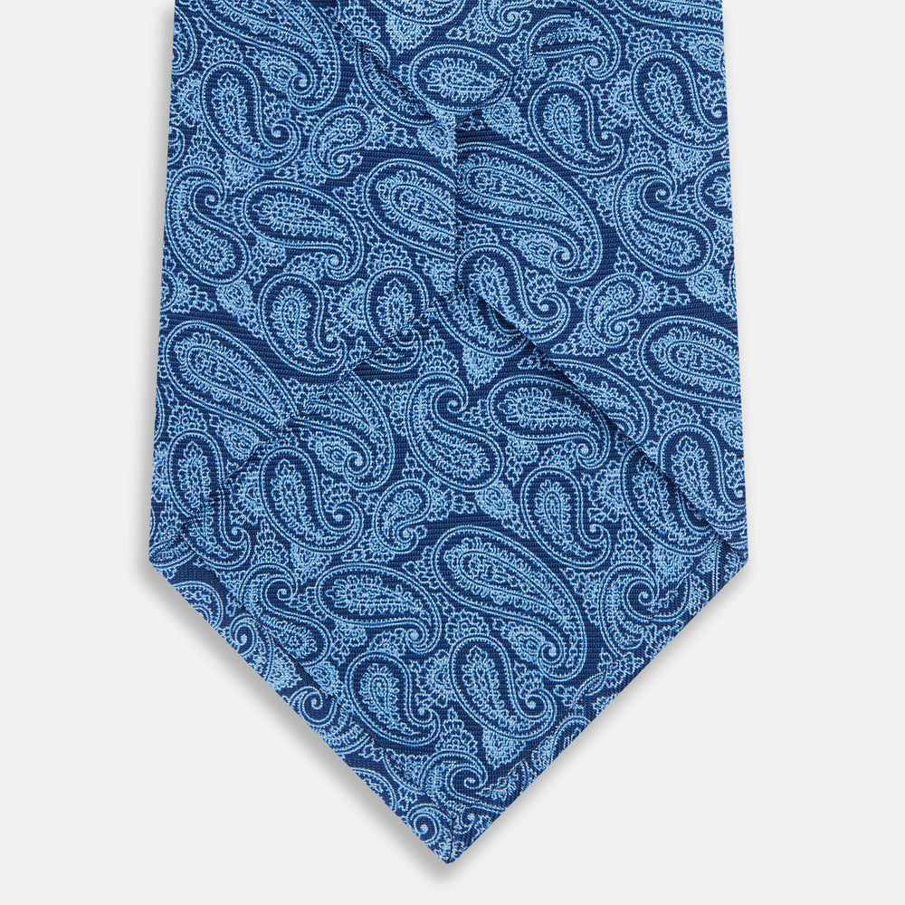 The Turnbull & Asser Azzurro Paisley Silk Tie features an intricate light blue pattern and is crafted from fine English silk—an elegant men's necktie displayed rolled up on a plain white background.