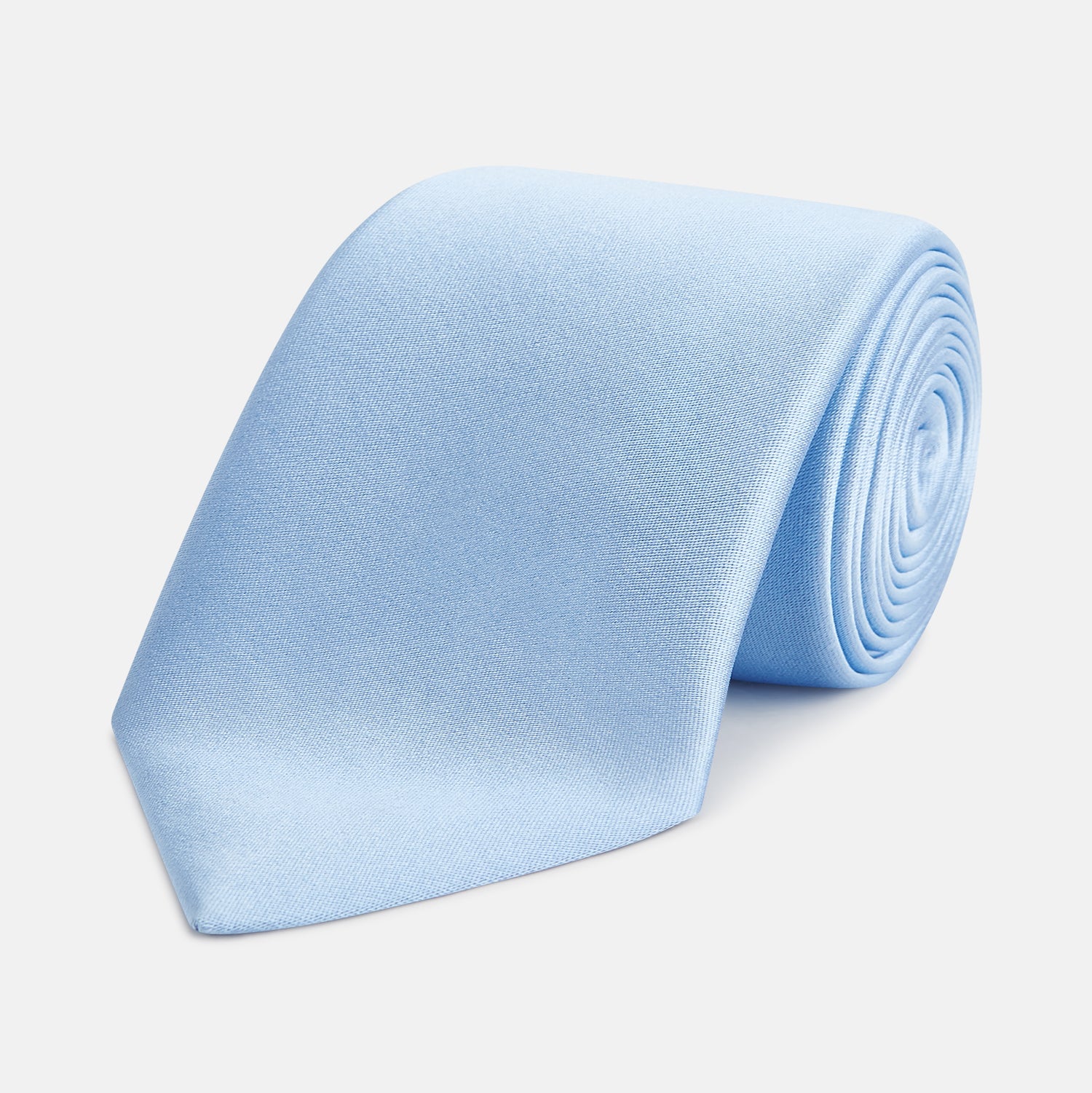 View 1 of product The Turnbull & Asser SATIN RIVER TIE, a neatly rolled light blue silk accessory with a smooth matte finish, is displayed against a plain white background.
