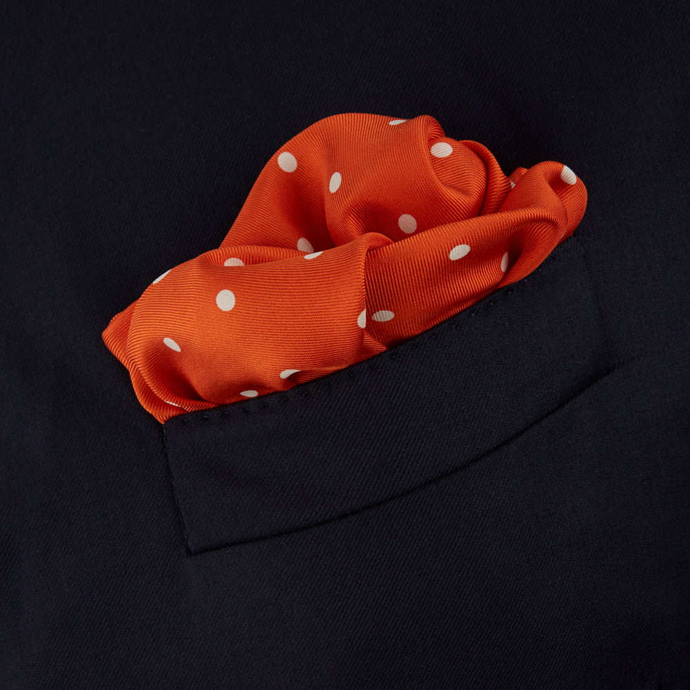The Orange Spot Silk Pocket Square by Turnbull & Asser features evenly spaced white polka dots and the brand’s name in one corner, making this dapper accessory a standout addition to any outfit.