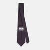 View 4 of product The Turnbull & Asser Magenta and Navy Square-Patterned Silk Tie is neatly rolled on a plain light background.