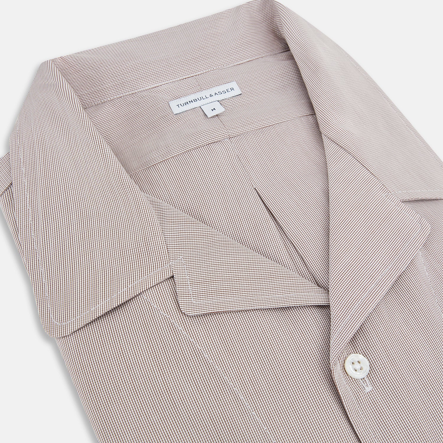 View 2 of product The Turnbull & Asser Brown Micro Check Quarzo Nightshirt is a long-sleeve shirt dress inspired by classic sleepwear, featuring a collar, chest pocket, upper front buttons, and a subtle micro check pattern on a white background.