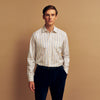 View 1 of product A man with short brown hair stands against a beige background in a Turnbull & Asser Blue and Off-White Stripe Cotton Weekend Fit Finch Shirt, featuring vertical stripes and a Derby collar, paired with dark pants. One hand is in his pocket; he has a neutral expression.