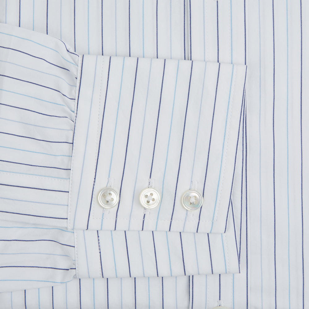 The Turnbull & Asser Blue Wide Pinstripe Mayfair Shirt is a long-sleeved, collared, button-down style crafted from organic cotton, featuring wide blue pinstripes on a white background.