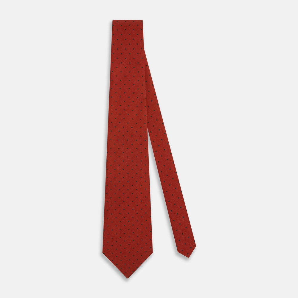 The Turnbull & Asser Red and Navy Polka Dot Silk Tie is elegantly rolled on a white background, highlighting classic British craftsmanship.