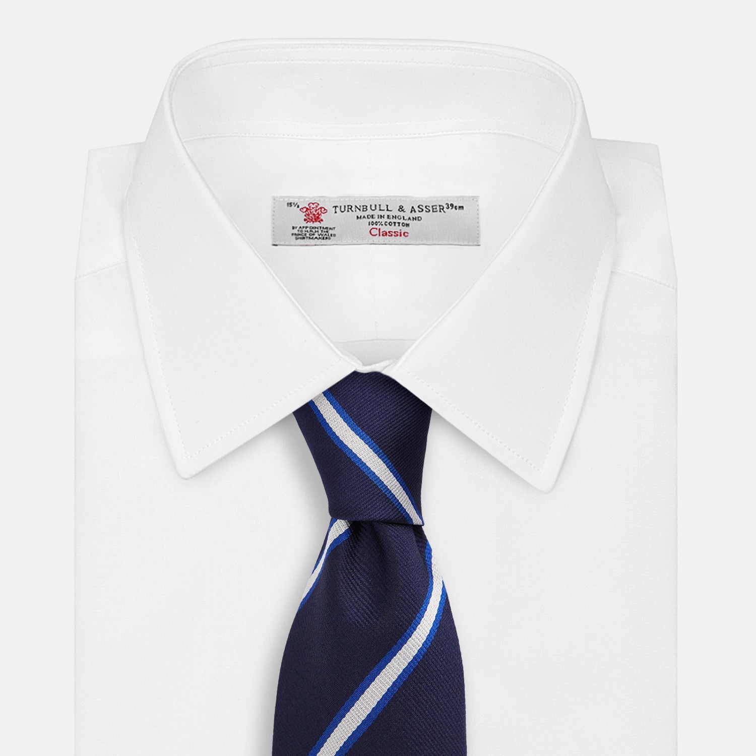 View 2 of product The White and Navy Blazer Silk Tie by Turnbull & Asser features diagonal white and light blue stripes on navy silk, shown rolled on a white background. A refined choice to complement any office shirt.
