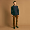 View 1 of product A man stands against a beige background wearing the Turnbull & Asser Navy Weekend Fit Cotton & Wool Shirt with a Derby collar and 1 button cuffs, paired with brown pants and black shoes, looking to the side with a neutral expression.