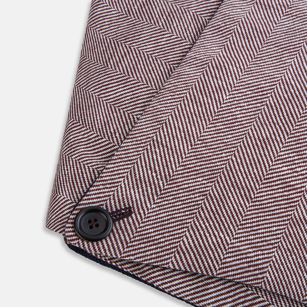 The Turnbull & Asser Burgundy Herringbone Silk and Linen Neck Warmer features a rich herringbone pattern, dark lining, and button closure, shown on a white background—a refined formal accessory.