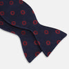 View 3 of product Elevate your formalwear with the Turnbull & Asser Navy and Burgundy Motif Silk Bow Tie, featuring a subtle ribbed texture and repeating red geometric motifs.