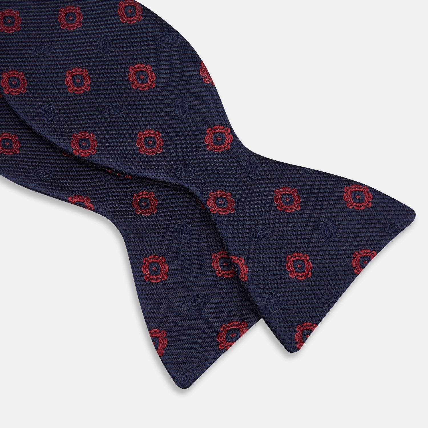 View 3 of product Elevate your formalwear with the Turnbull & Asser Navy and Burgundy Motif Silk Bow Tie, featuring a subtle ribbed texture and repeating red geometric motifs.