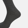 View 4 of product The image shows a single Turnbull & Asser Dark Steel/Navy Polka Dot Mid-Length Sock standing upright on a plain white background, featuring a ribbed cuff and a smooth, seamless finish.