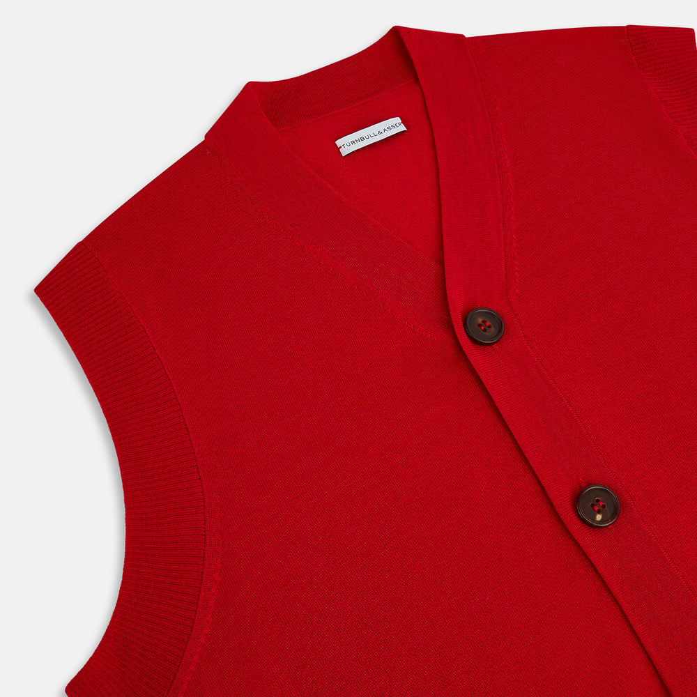 The Turnbull & Asser Red Fine Merino V-Neck Sleeveless Cardigan features a collarless neckline, two front pockets, and five dark buttons, shown on a plain white background.