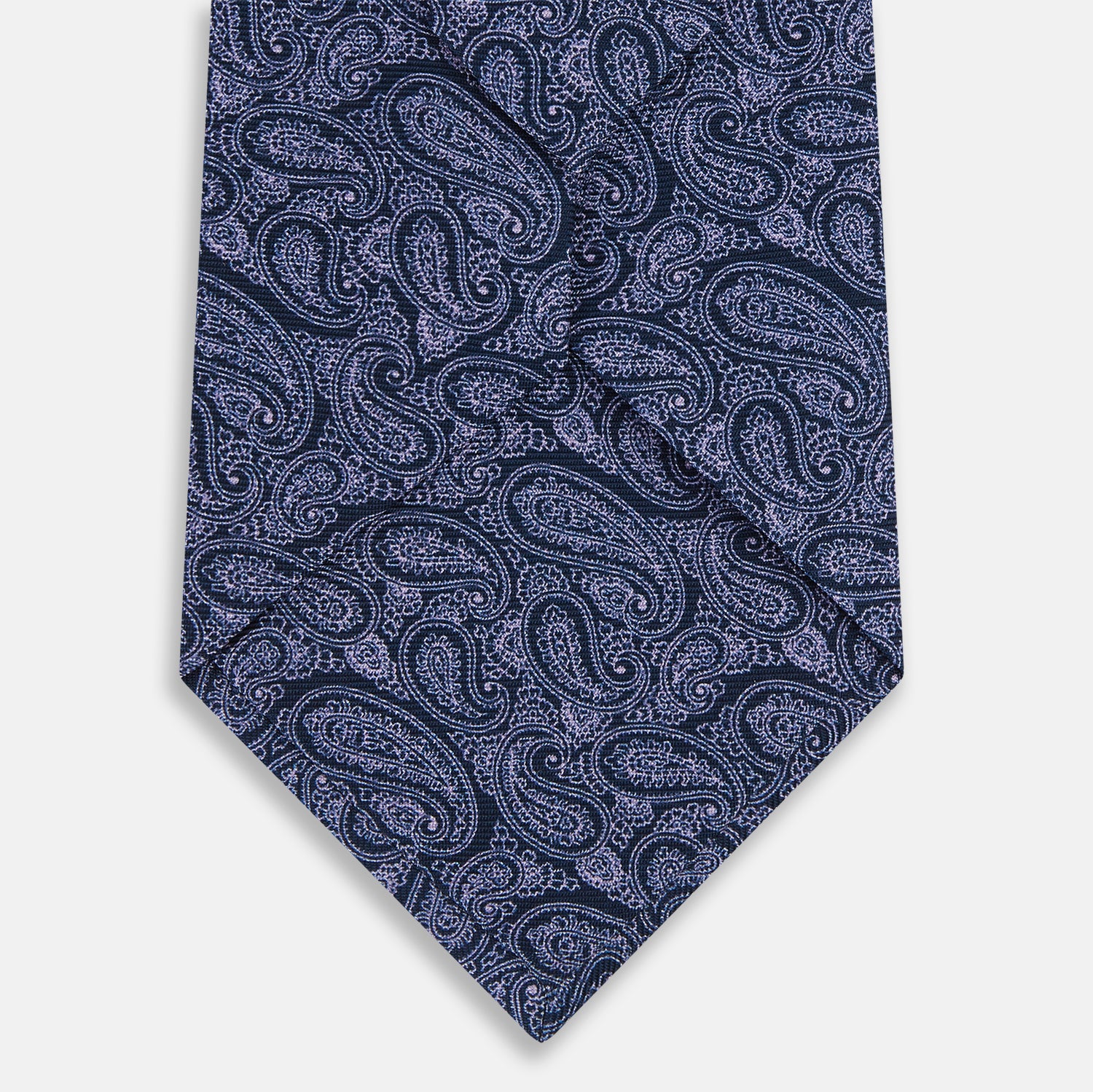 View 3 of product The Turnbull & Asser Navy Paisley Printed Silk Tie, featuring an intricate light lavender paisley design, is shown rolled up on a plain white background.