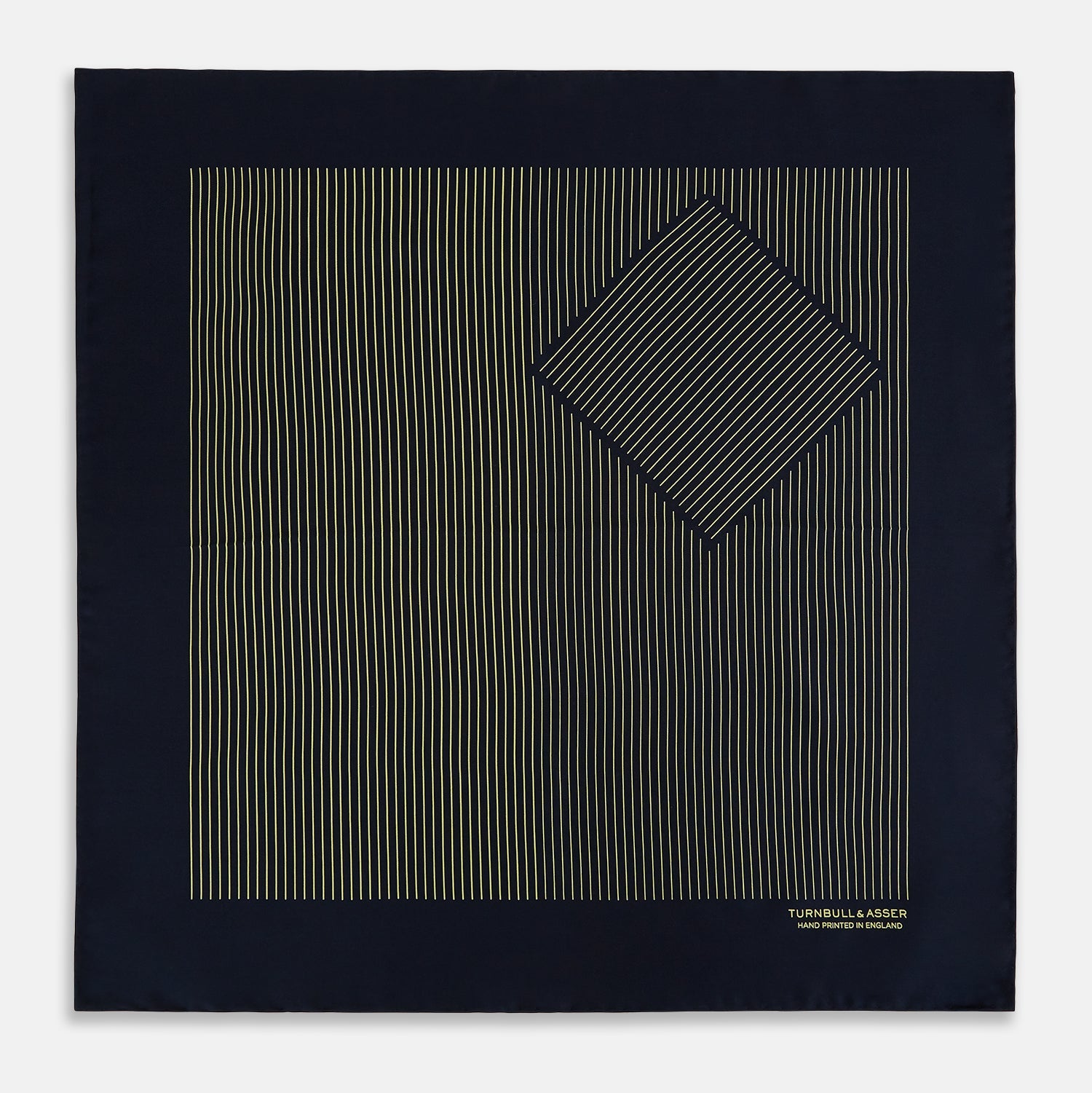 View 3 of product The Turnbull & Asser Navy and Gold Stripe Silk Pocket Square features light yellow vertical stripes, a folded corner, and "TURNBULL & ASSER HAND PRINTED IN ENGLAND" in gold at the bottom right.