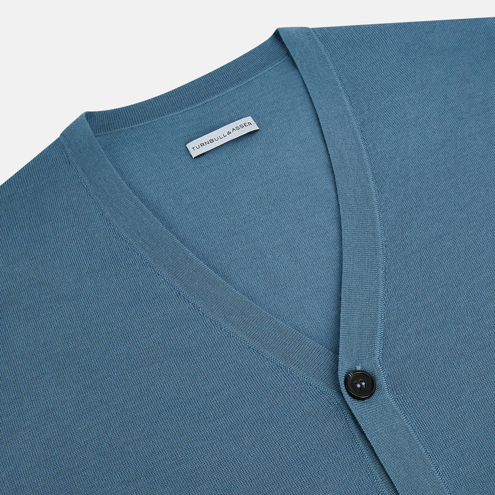 The Turnbull & Asser Pale Blue Fine Merino V-Neck Cardigan features long sleeves and five black buttons, showcased on a plain white background.