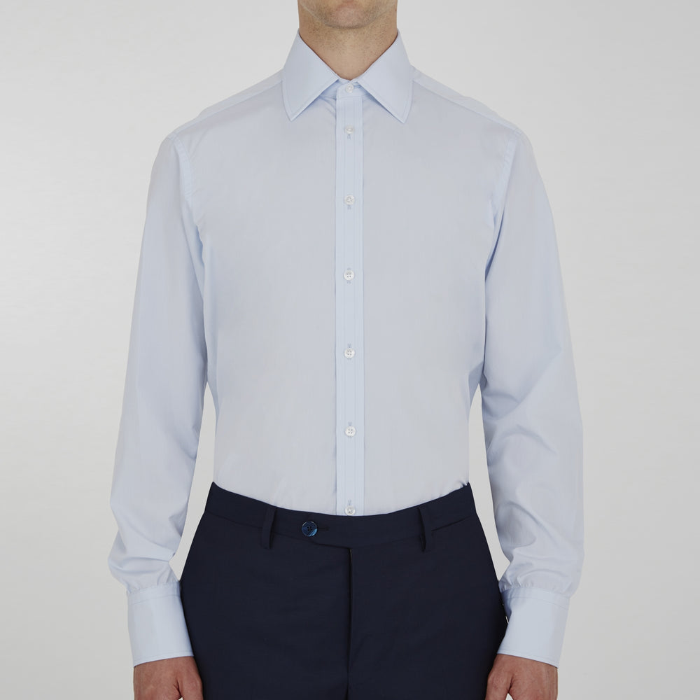 The Turnbull & Asser Two-Fold 120 Light Blue Shirt features a T&A collar, 3-button cuffs, white buttons, front pocket, and inner collar label. It is displayed neatly folded on a plain white background.