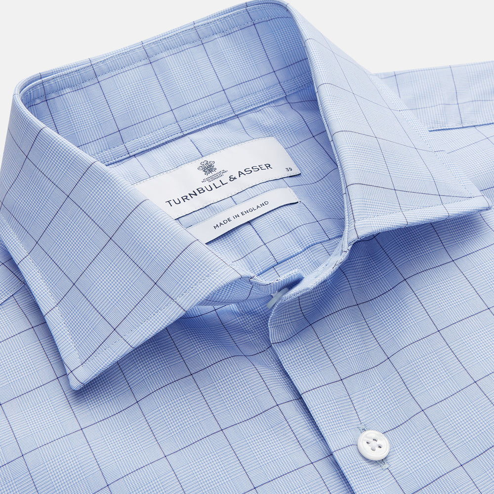 The Blue Prince of Wales Check Mayfair Shirt by Turnbull & Asser features a light blue check pattern, white buttons, and a classic collar. Crafted from premium Italian cotton, it is displayed on a plain white background.