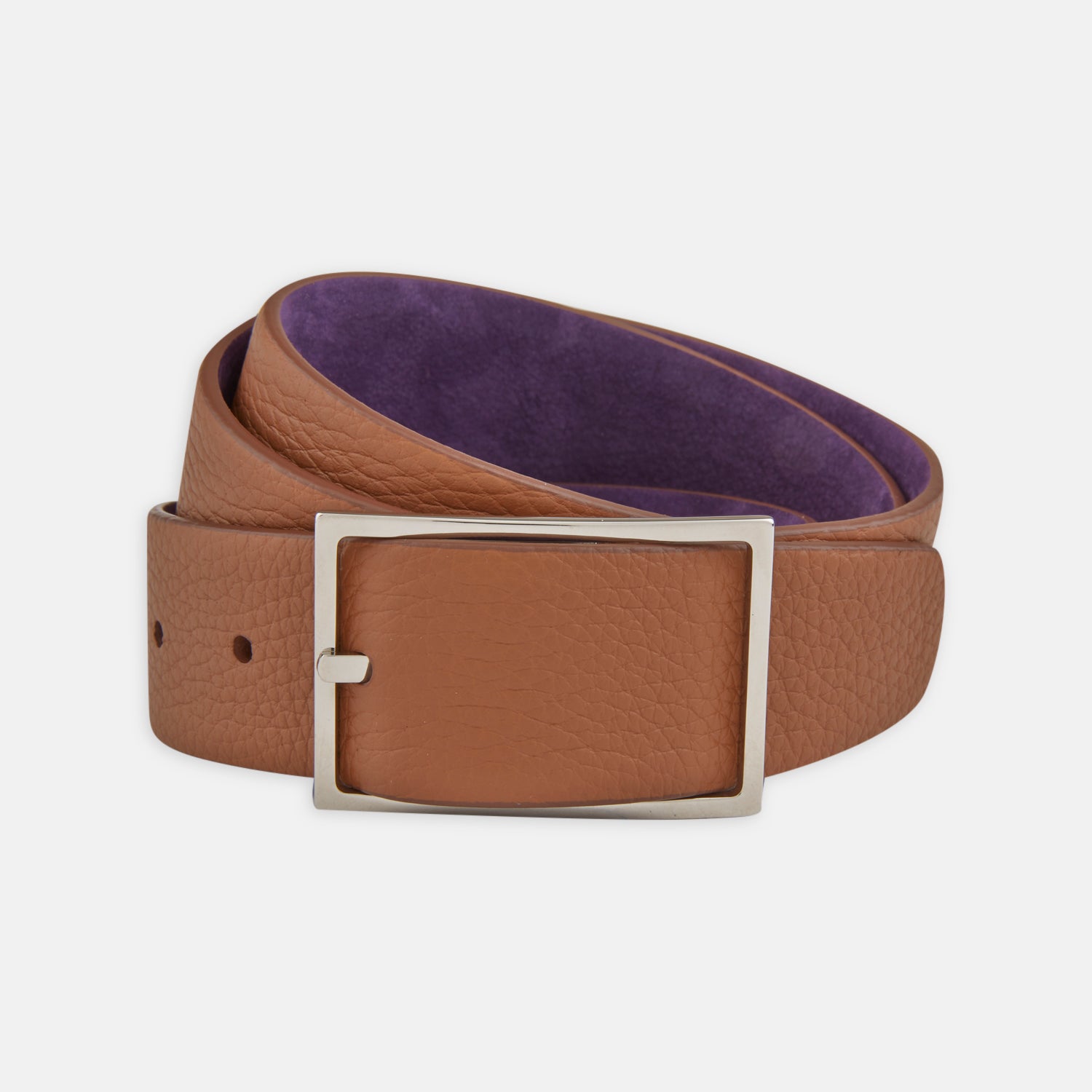 View 1 of product The Turnbull & Asser Lagun grained Nubuk Reversible Leather Belt features a tan finish, silver rectangular buckle, and purple inner lining, shown coiled on a white background.
