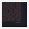 View 4 of product The Turnbull & Asser Navy and Blush Stripe Silk Pocket Square features thin blush stripes on navy silk, finished with "TURNBULL & ASSER HAND PRINTED IN ENGLAND" in the corner, highlighting its refined English craftsmanship.