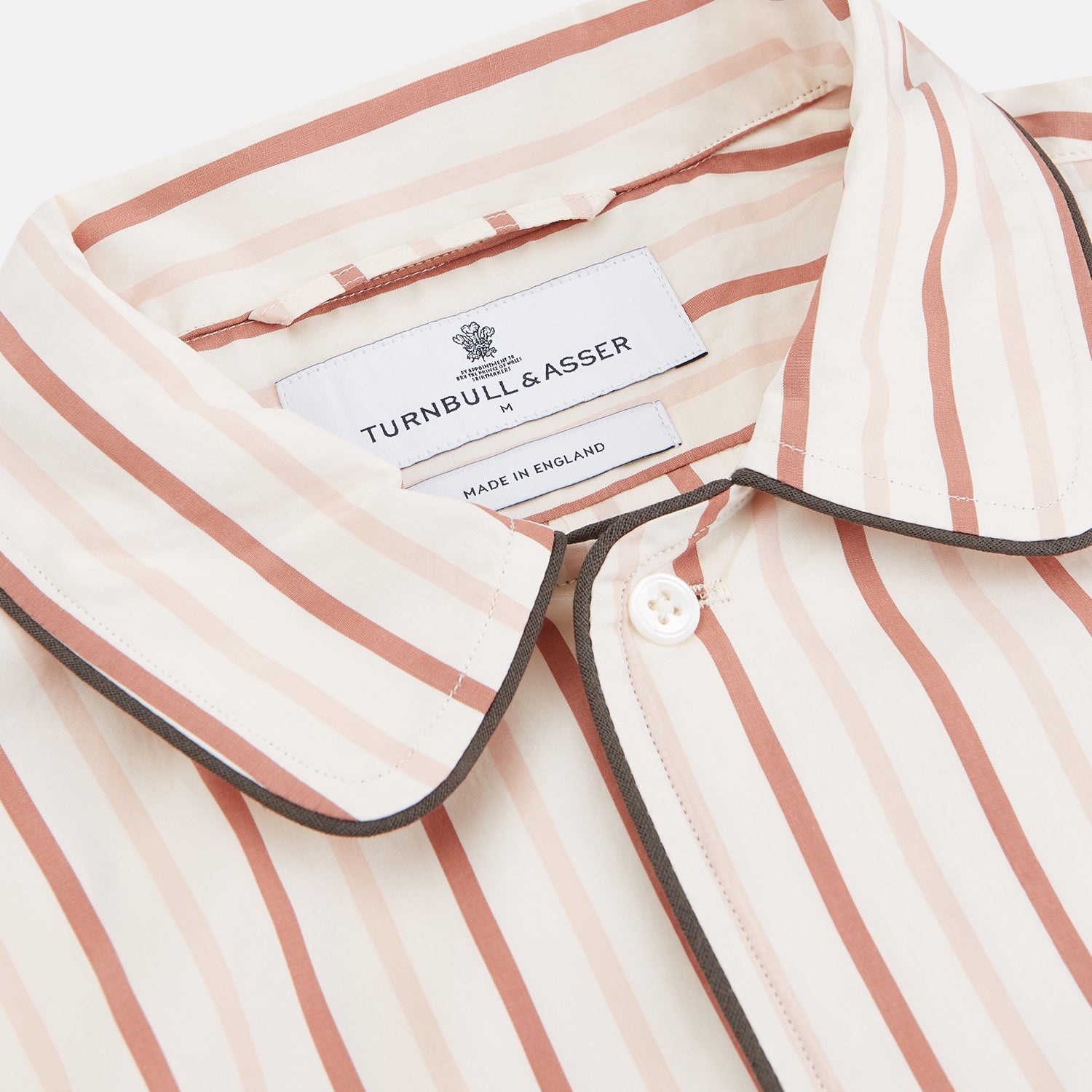 View 2 of product The Burgundy Multi Striped Cotton Sussex Nightshirt by Turnbull & Asser features long sleeves, knee length, a pointed collar, chest pocket, burgundy and beige stripes on white, buttoned cuffs, and a curved hem for classic sleepwear style.